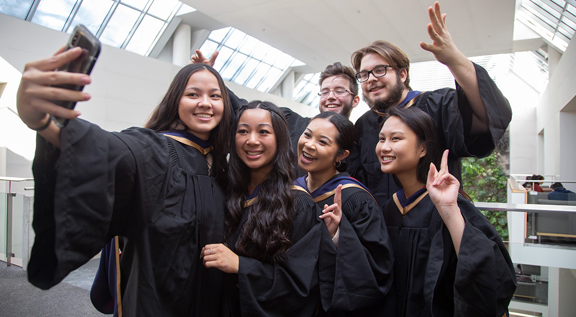 Grad selfie six students in grad gowns taking a selfie