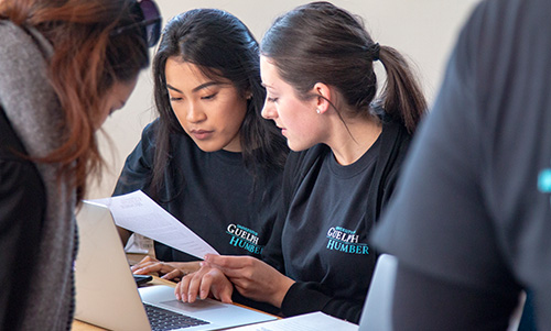 Emerge project Two female students reading paper document
