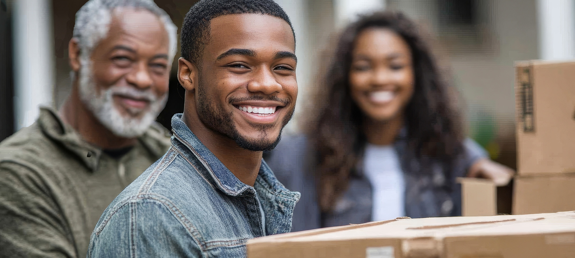 student holding moving box with supporters in background