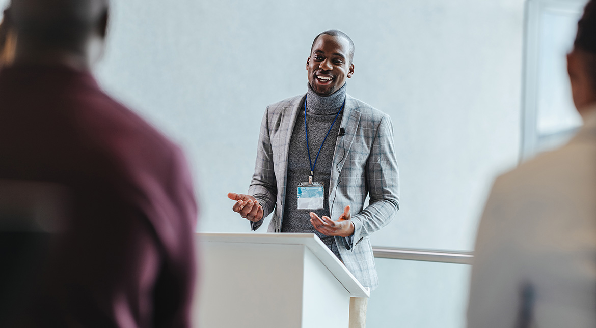 Presentation man wearing a suit at podium speaking to audience