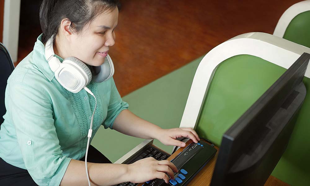 Woman using computer with braille display