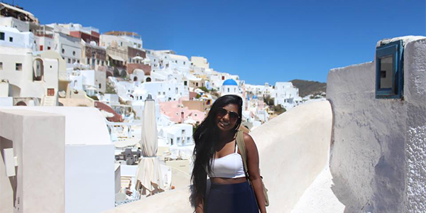 Student smiling in front of Greek houses