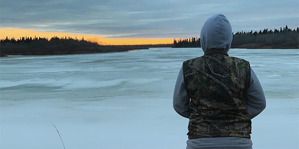 Student Student looking out over frozen lake with sunset