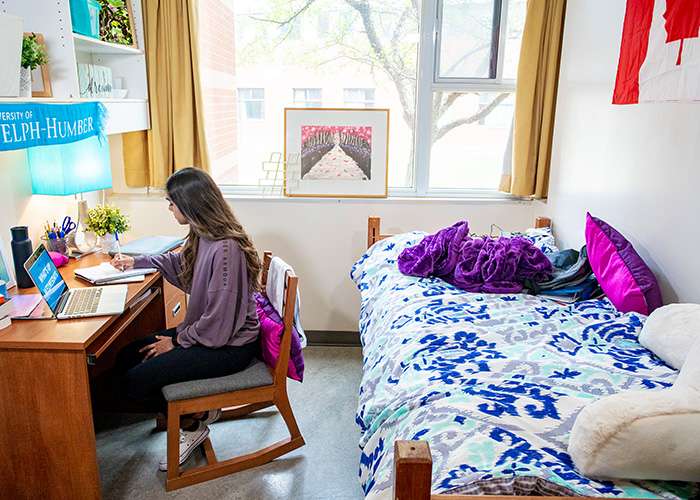 Inside a residence room, a student is working at a desk