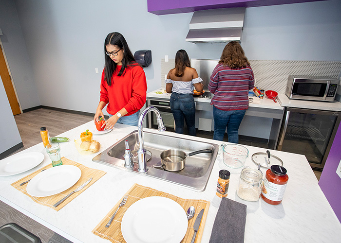 Three students using the kitchen