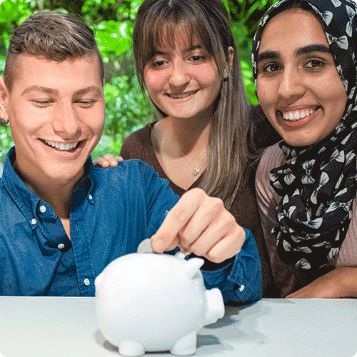 Three students put coins into piggy bank
