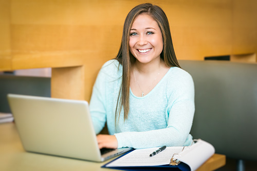 Student using laptop and smiling
