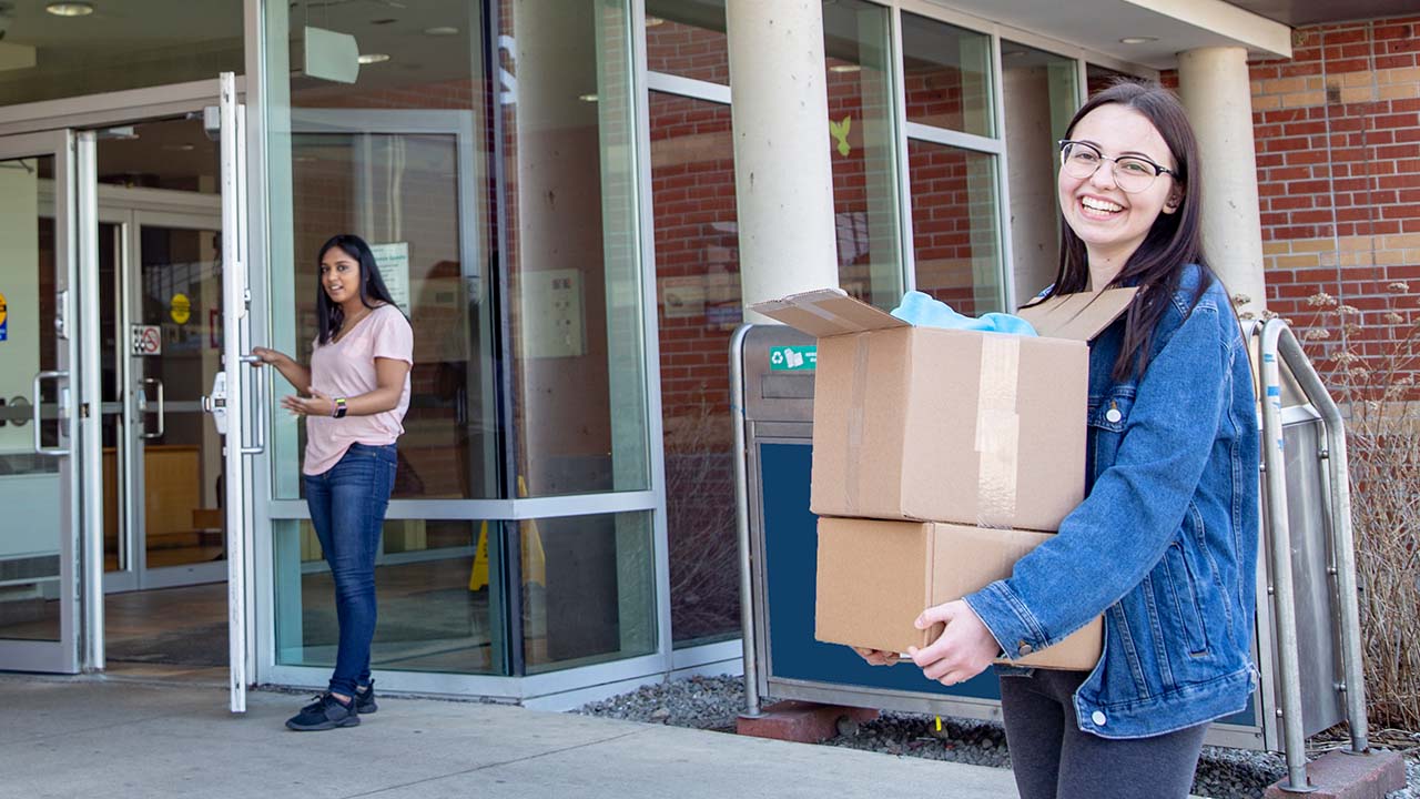 Student carrying box into residence