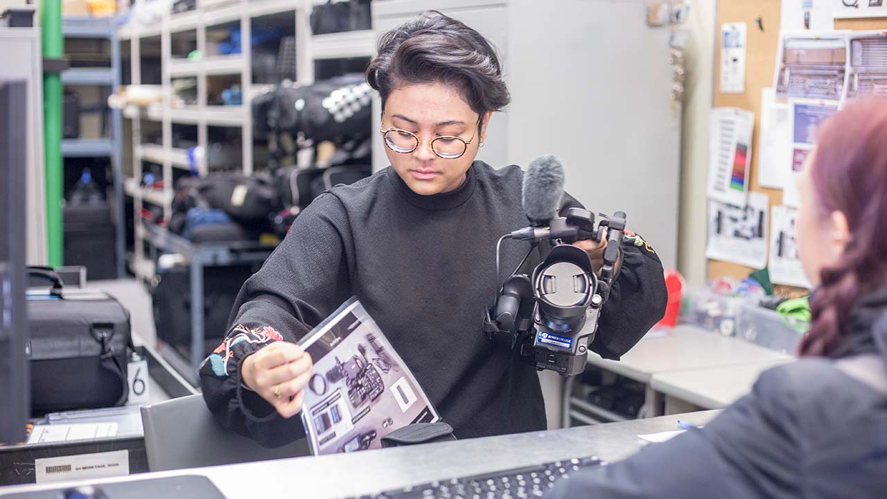 student with camera in media cage