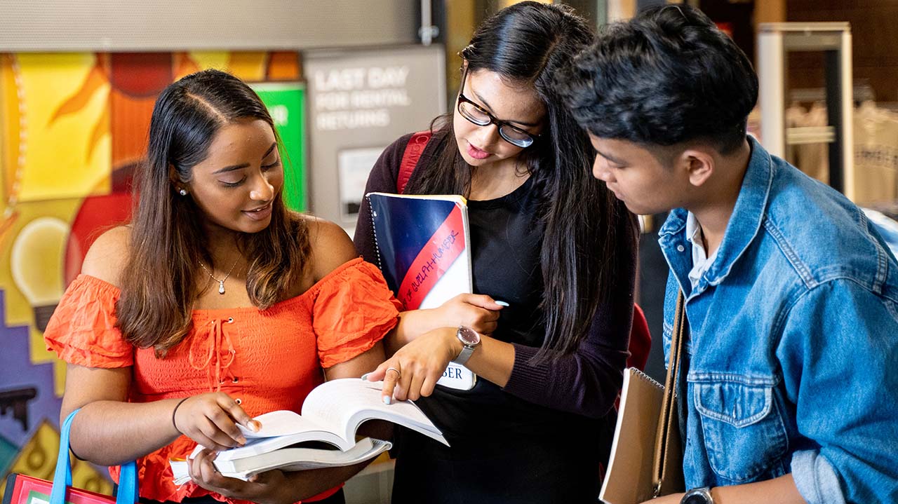 three students looking at textbook