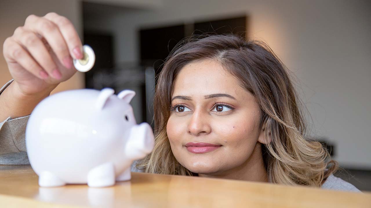 Woman putting a coin into a piggy bank