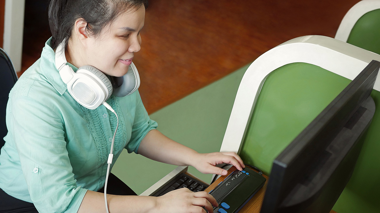 Woman using computer with braille display