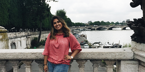 Student standing on a bridge smiling