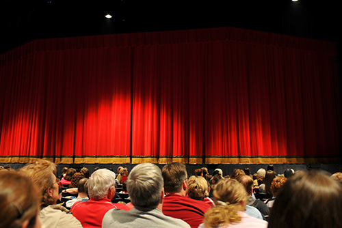 People looking at the stage of a play.  The curtains are down.