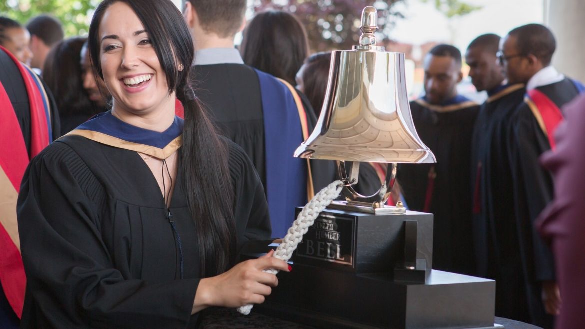 Graduate ringing the UofGH traditional bell