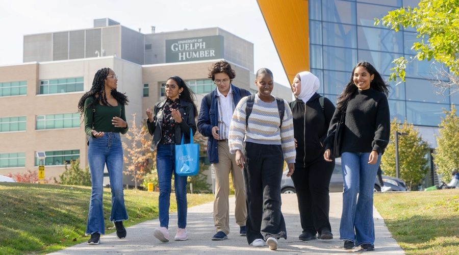 Six people walking towards the camera with the University of Guelph-Humber building in the background