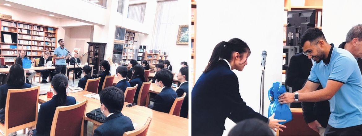 UofGH student presenting in front of high school students in Japan and presenting a gift to one of the high school students