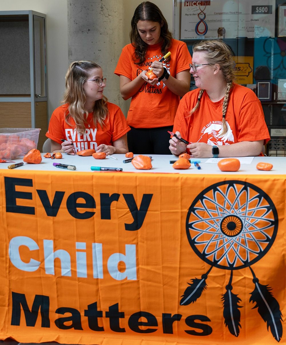Three students at an Every Child Matters booth