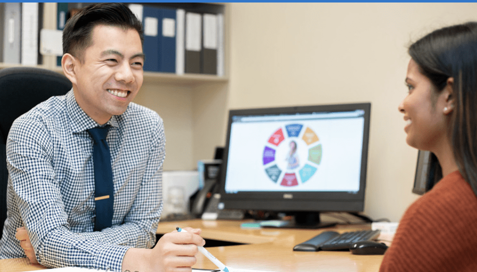 A student sits across from a smiling advisor in their office