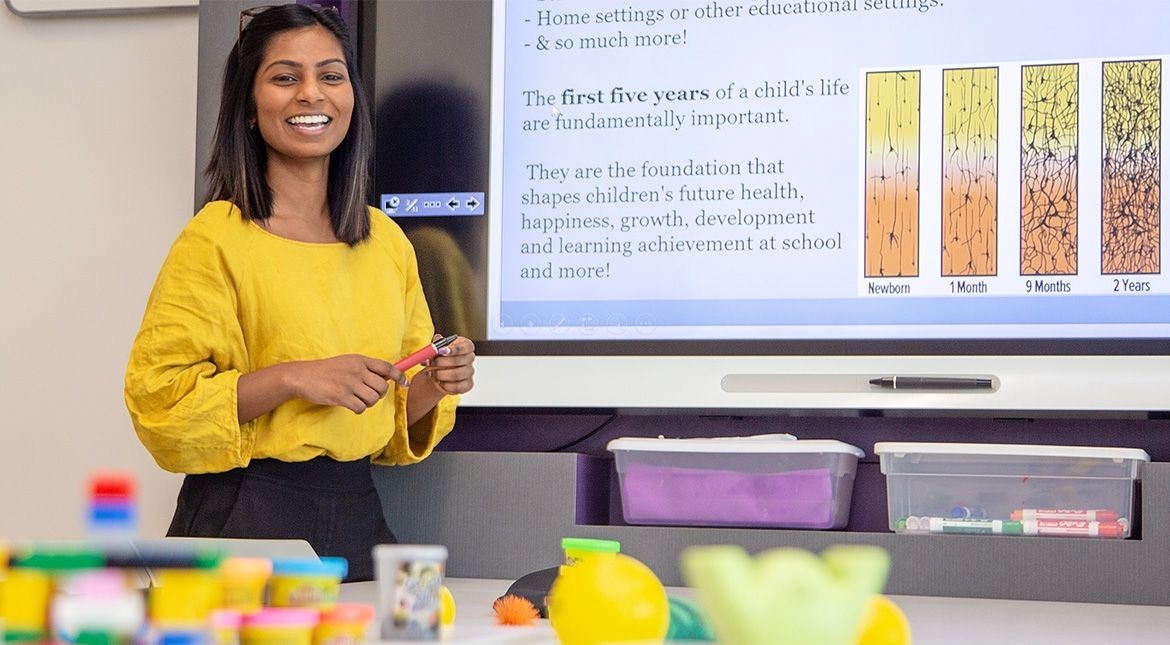 Female student in yellow top next to screen