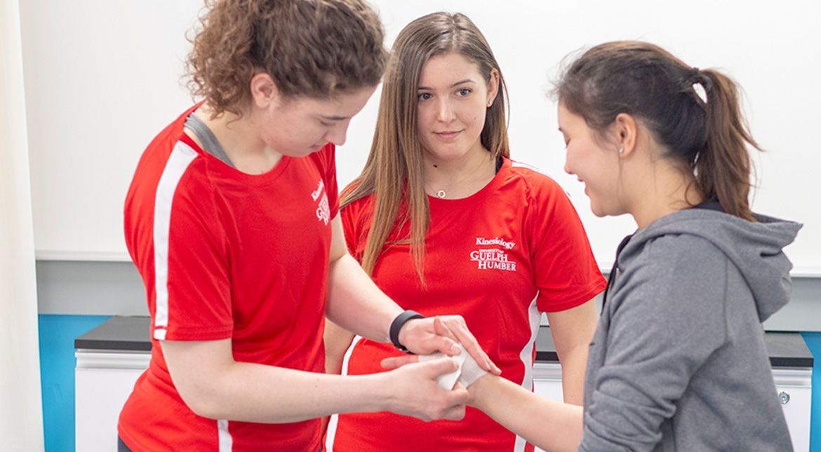 Two students taping a person's injured wrist
