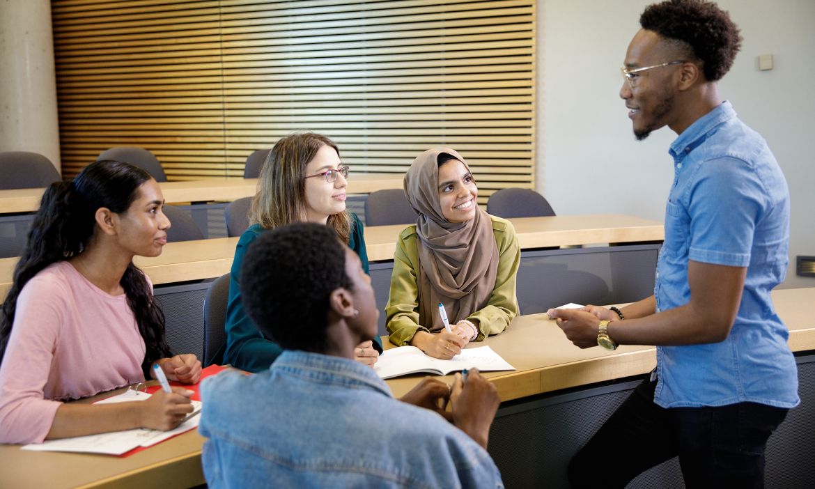 four students listening to a teacher