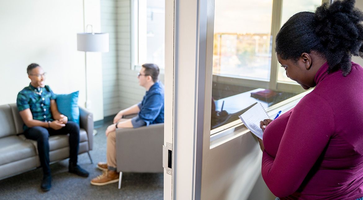 student watching counselling session behind two way mirror