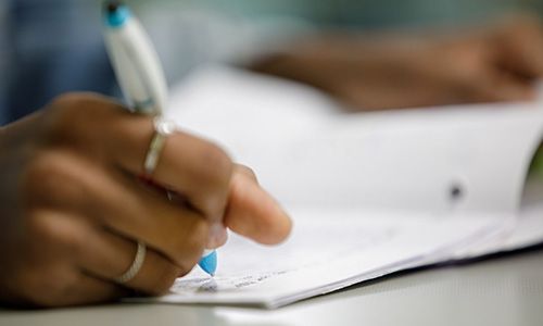 close up of student's hand writing in notebook