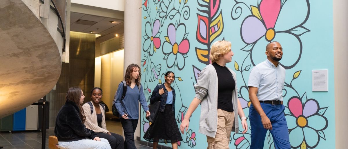 Students walking past the Indigenous art mural in the atrium
