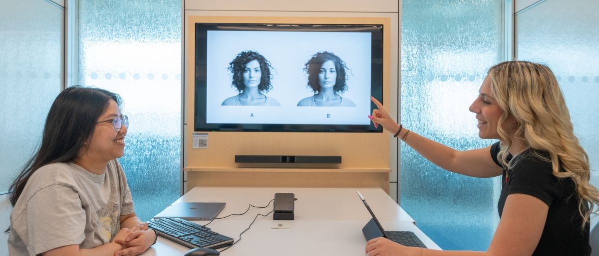 Two students using facial recognition software on a screen while sitting at a desk