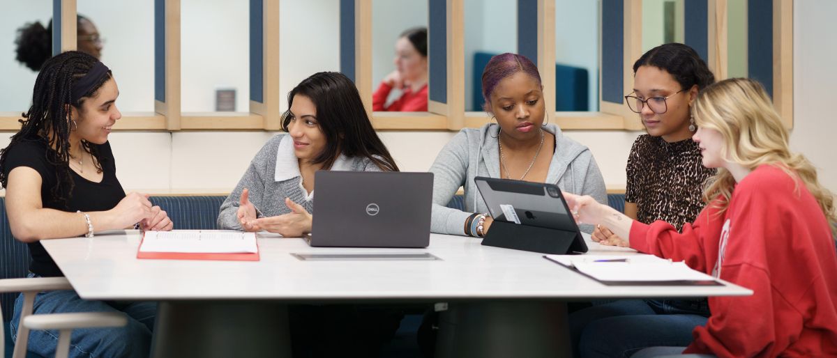 five female students looking at laptops