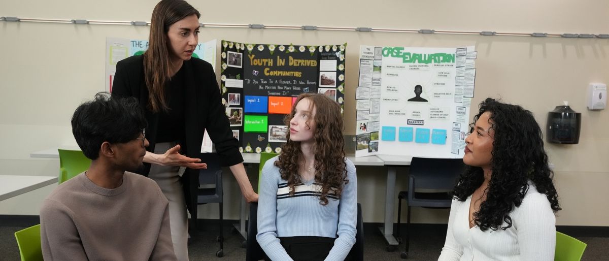 program chair talking to three students in chairs