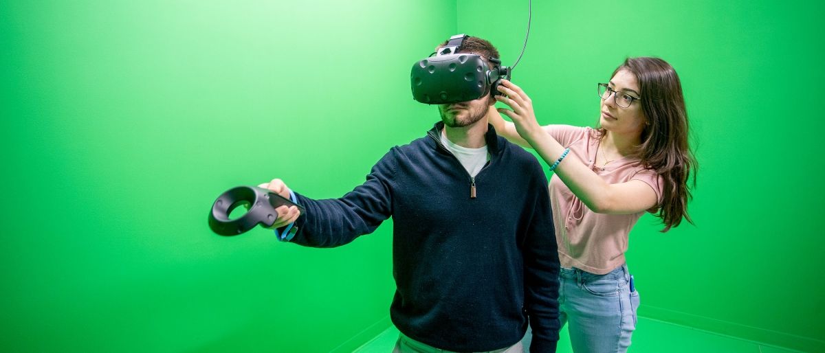 VR studio Student adjusting virtual reality headset in green room