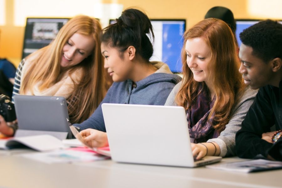 Group of students smiling looking at laptop