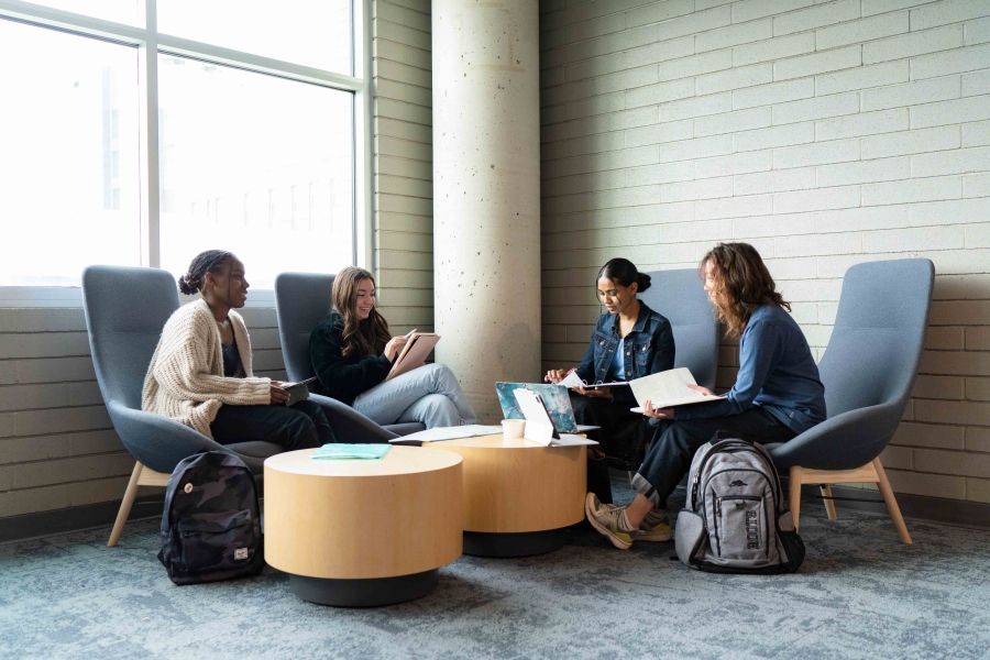 Four students sitting around a round coffee table with notes out on their laps