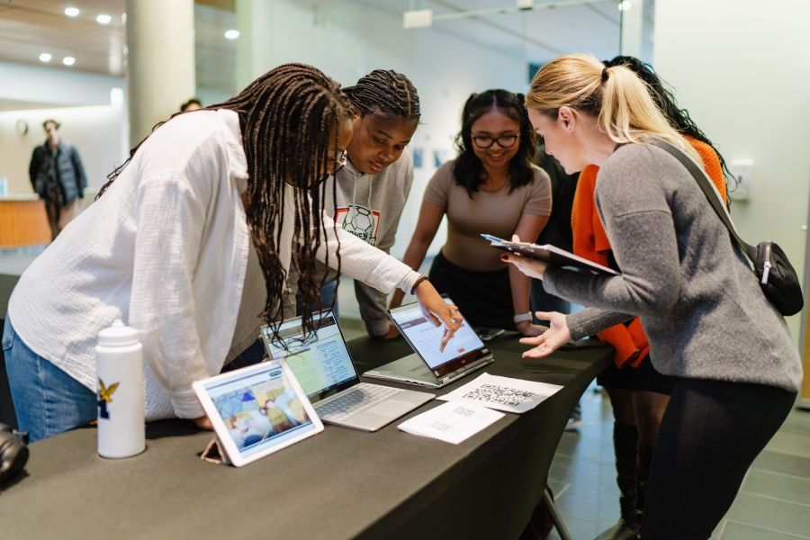 Group of students around table looking at projects at showcase