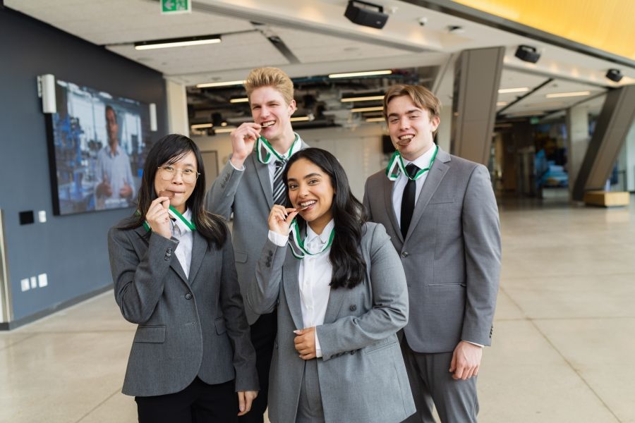 Four students biting award medals for fun
