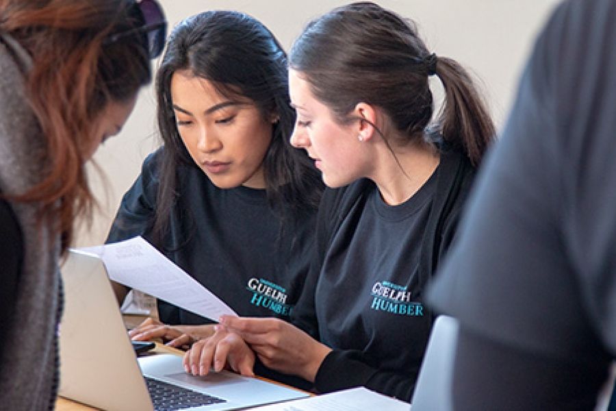 Two female students reading paper document