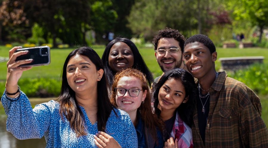 Group of 5 students taking a selfie photo in nature