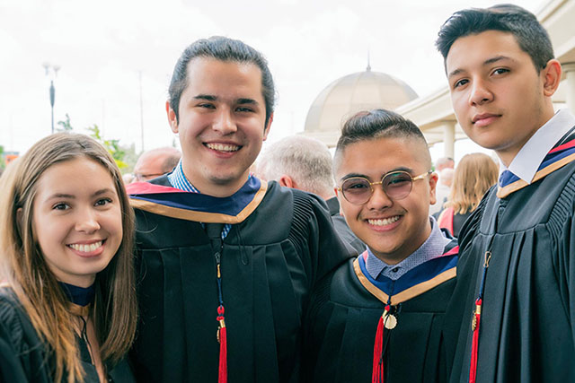 Four graduates celebrate outside