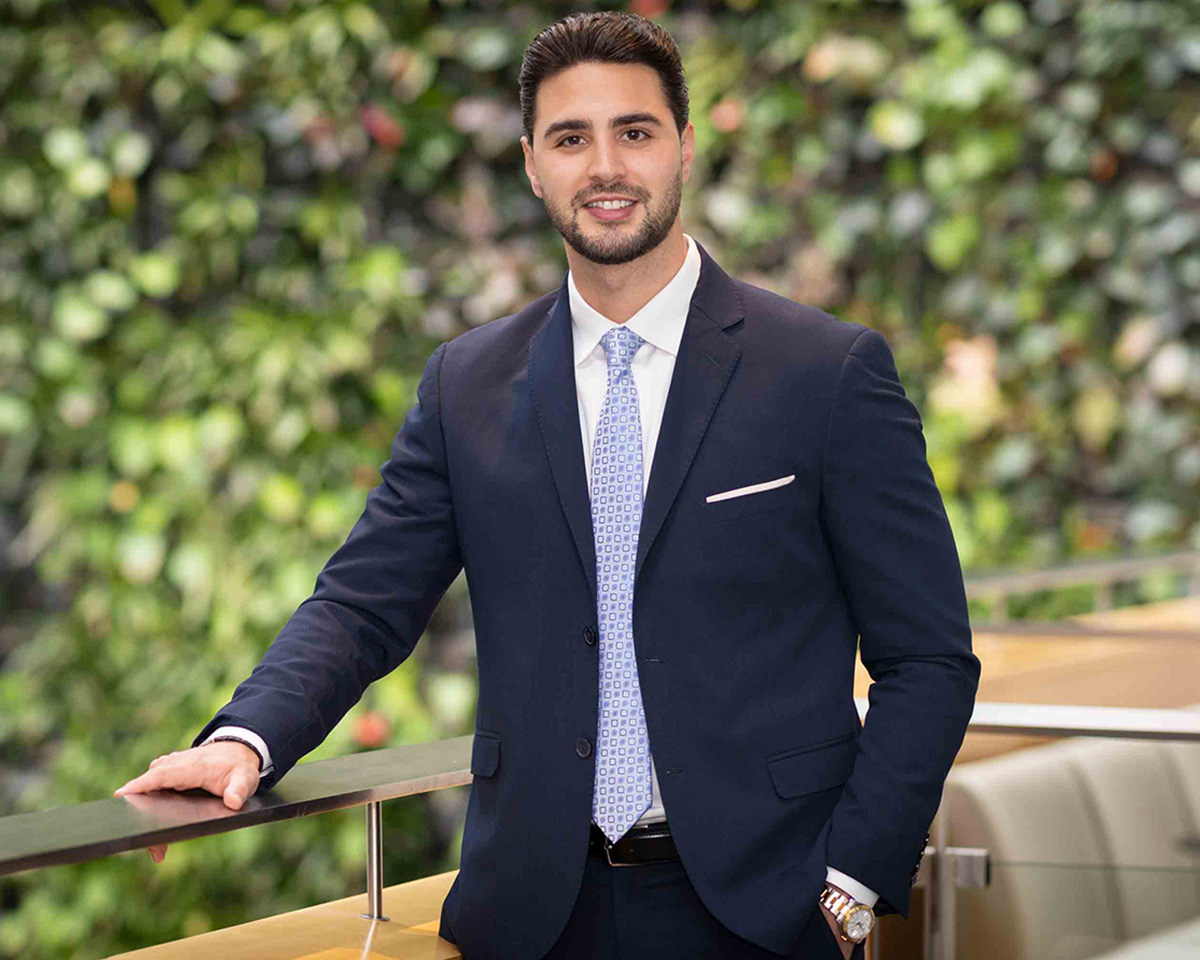 man in blue suit in front of plant wall